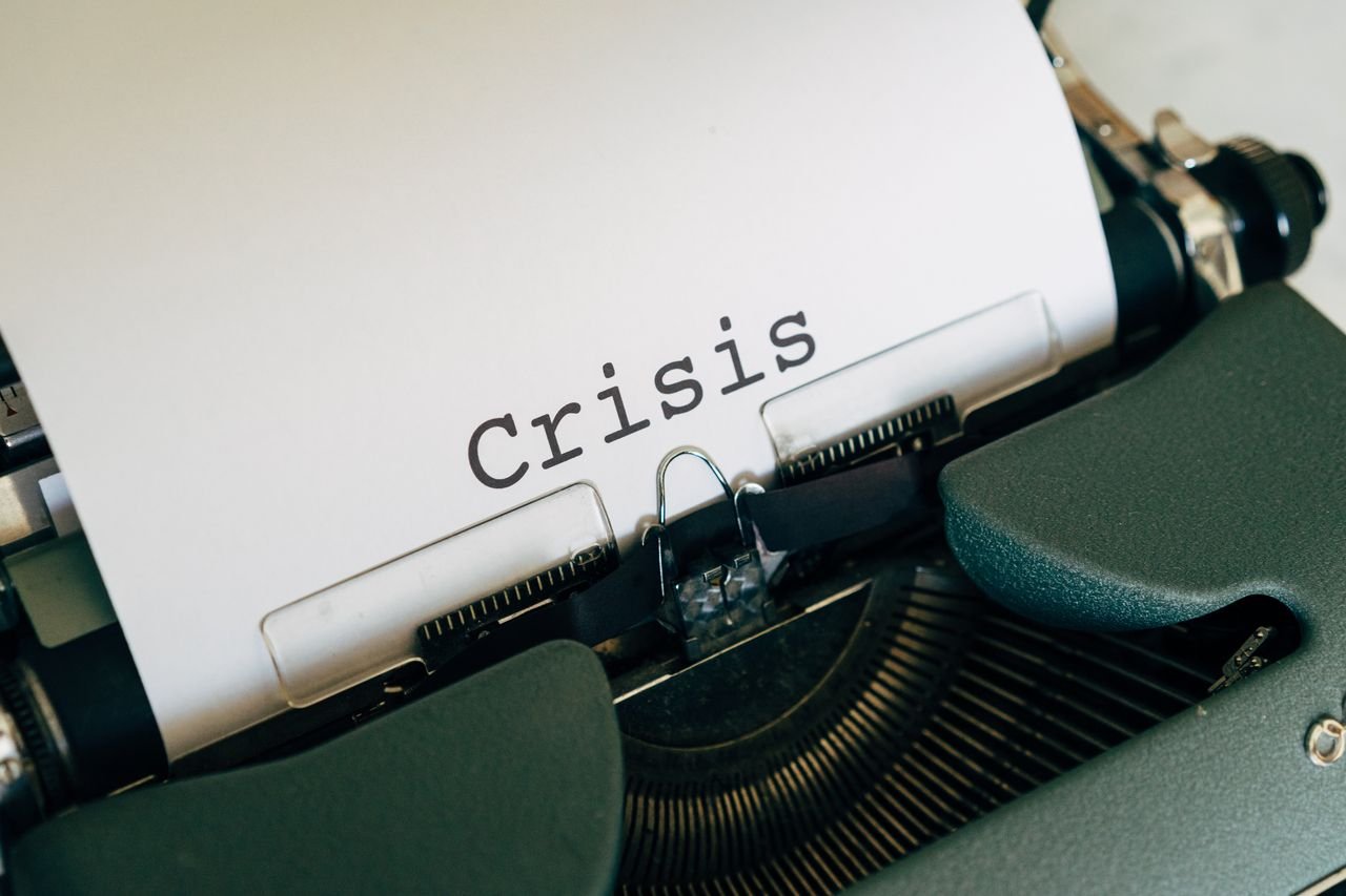 Close-up of a vintage typewriter with the word Crisis typed on paper.